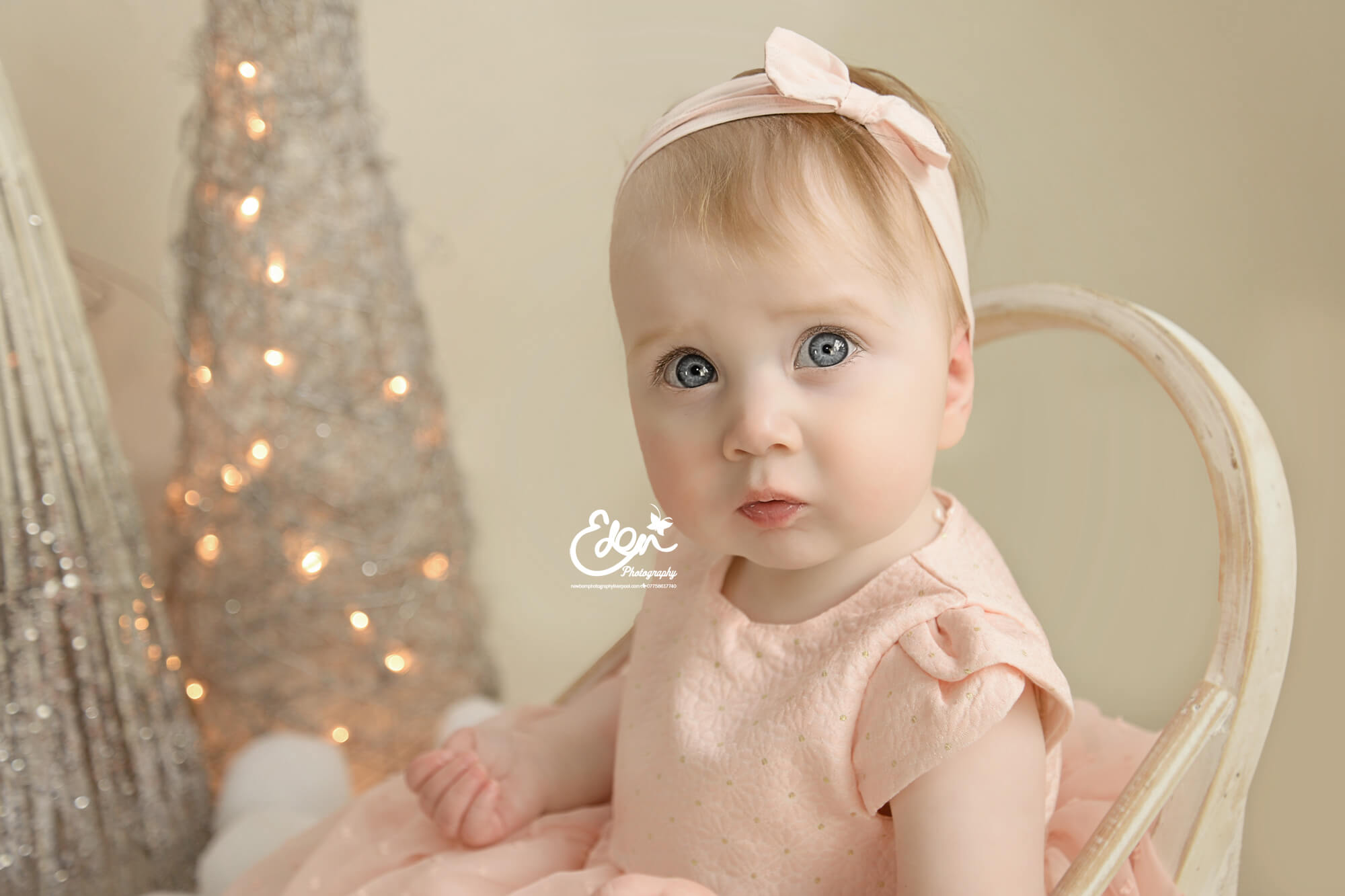 Baby girl sitting in front of Christmas Decor.